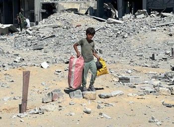 طفل يحمل ماتبقى من المنزل بعد القصف