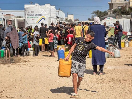 طفل يحمل قروره بعد الحصول على المياه