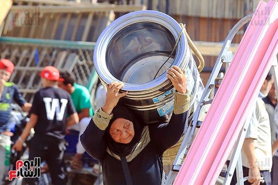 سيدة تحمل غسالة بعد شرائها من الخردة