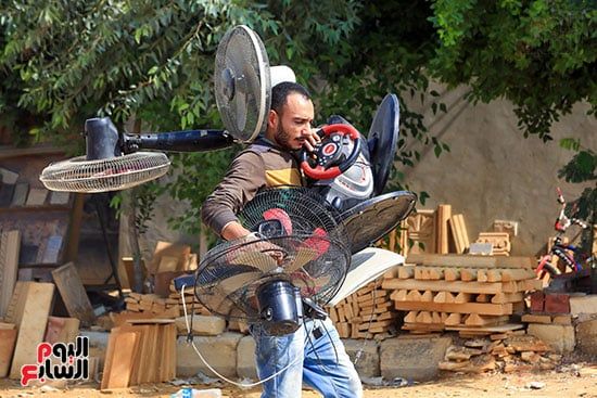تاجر يقوم بحمل عدد من المراوح الكهربائية