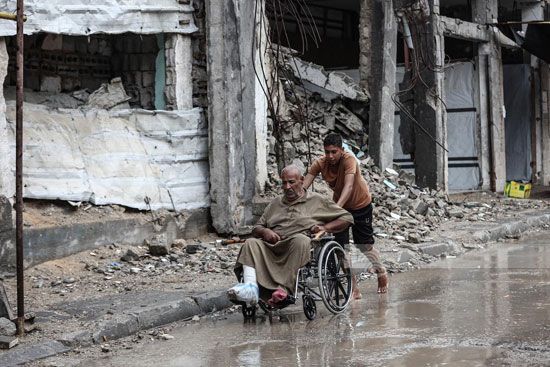 رجل مسن على كرسى متحرك وسط مياه الأمطار رجل مسن على كرسى متحرك وسط مياه الأمطار