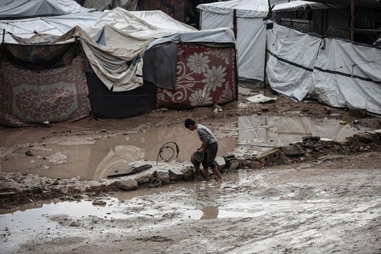 طفل يحالو بناء سد لمنع تدفق مياه الأمطار الى الخيام طفل يحالو بناء سد لمنع تدفق مياه الأمطار الى الخيام