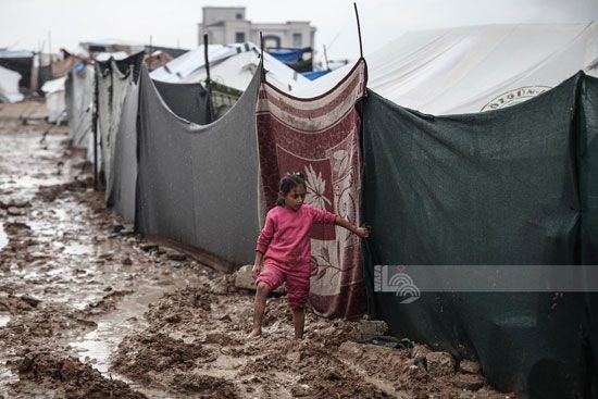 طفله تسير وسط الطين الناجم عن مياه الأمطار طفله تسير وسط الطين الناجم عن مياه الأمطار