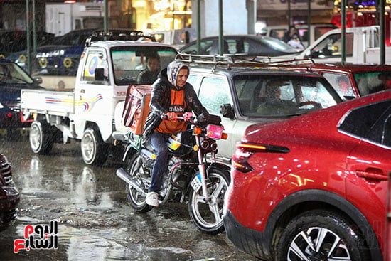 عامل الدليفرى يقود دراجة نارية تحت المطر عامل الدليفرى يقود دراجة نارية تحت المطر