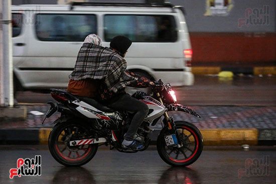 مواطن ووالدته على دراجة نارية وقت المطر مواطن ووالدته على دراجة نارية وقت المطر