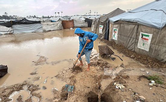 فلسطينى يحاول عمل سد لمنع تدفق المياه الى الخيام فلسطينى يحاول عمل سد لمنع تدفق المياه الى الخيام