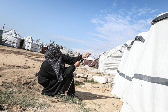 سيدة تقوم بشد الخيام لمحاولات العيش بها