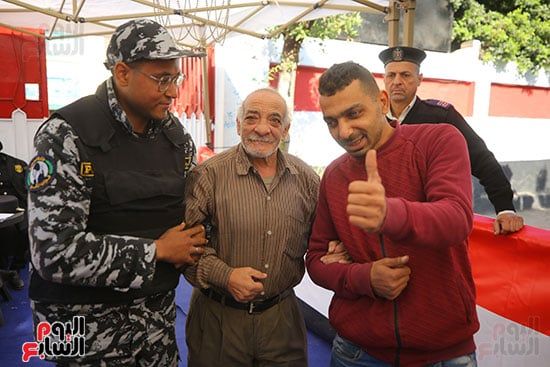 شرطي يساعد مسن أثناء العملية الأنتخابية شرطي يساعد مسن أثناء العملية الأنتخابية