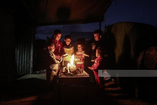 الأطفال يلتفون حول النار للتدفئة من برد الشتاء القارص