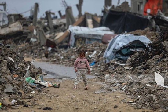 طفلة تسير وسط ركام المبانى ومياه الأمطار