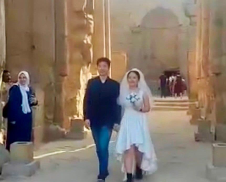 سائح صيني يحتفل مع زوجته بفستان وبدلة الزفاف في معبد الأقصر