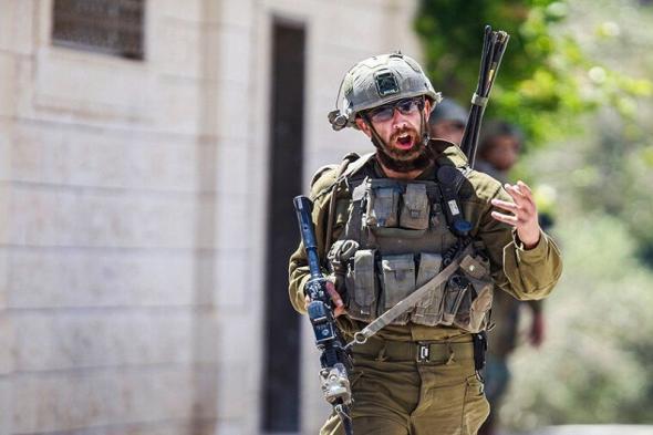 جندي إسرائيلي يلقي قنبلة عند مدخل وزارة الدفاع الإسرائيلية.